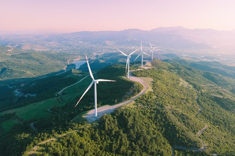 Turbiny wiatrowe położone na szczycie zielonego wzgórza.